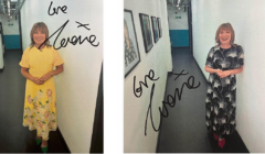 A woman in a floral dress smiling in a corridor with two signed photographs on the wall.