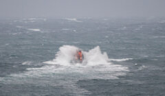 A lifeboat in rough sea conditions with waves crashing around it.