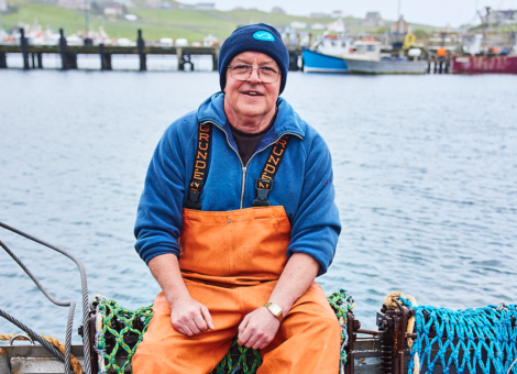 A man in overalls sitting on a boat.