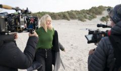 Woman being filmed on a beach for a production.