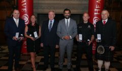 Group of individuals posing with awards at an event.