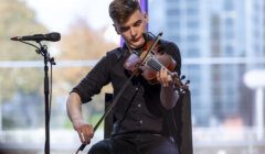 A violinist performing on stage with focus and intensity.