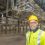 A man in a hard hat standing in a warehouse.