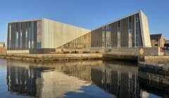 A modern building is reflected in a body of water.