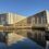 A modern building is reflected in a body of water.