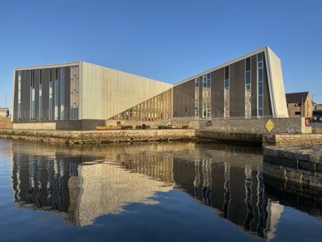 A modern building is reflected in a body of water.