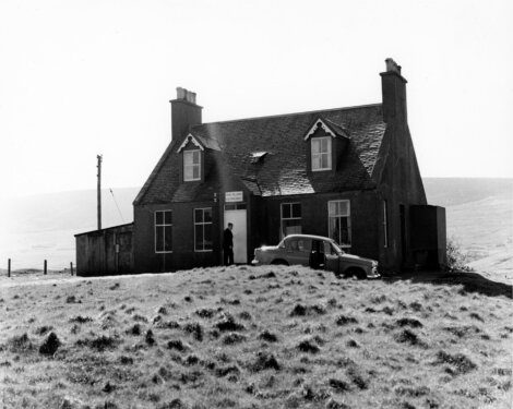 An old black and white photo of a house on a hill.