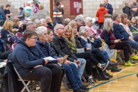 A crowd of people sitting in chairs in a gym.