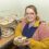 Woman presenting cupcakes at a bakery stand.