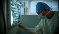 A medical professional analyzing radiological images in a dimly lit room.