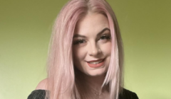 A woman with pink hair posing for a photo.