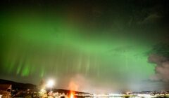 A green aurora bore over a city.