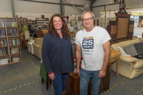 Two people standing in a room full of furniture.