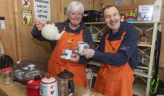 Two people in an orange apron holding tea cups.