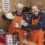 Two people in an orange apron holding tea cups.