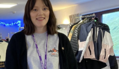 A woman standing in front of racks of clothes.