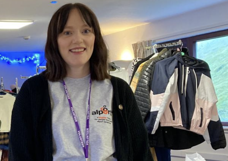 A woman standing in front of racks of clothes.