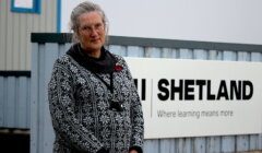 A woman standing in front of a shetland sign.