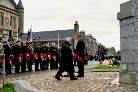 A group of people standing in front of a war memorial.