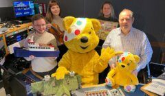 A group of people posing with a teddy bear.