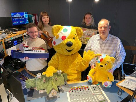 A group of people posing with a teddy bear.