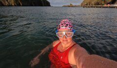 A woman in a red swimsuit taking a selfie in the water.