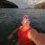 A woman in a red swimsuit taking a selfie in the water.