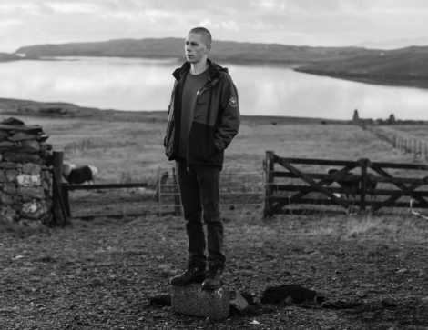 A man standing on a rock in front of a lake.