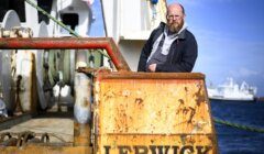 A man with a beard standing next to a boat.