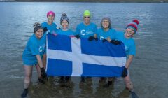 A group of people holding a scottish flag in the water.