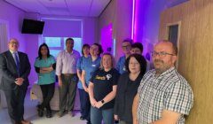 A group of people standing in a room with purple lights.