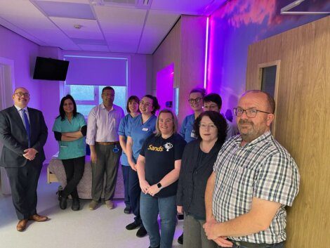 A group of people standing in a room with purple lights.