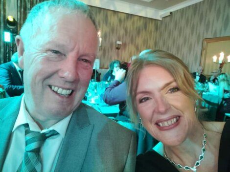 A man and woman posing for a photo at a formal event.