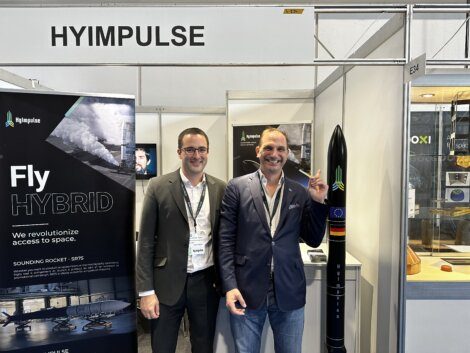 Two men standing in front of a booth at a trade show.