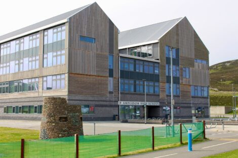 A building with a stone structure and grass field.