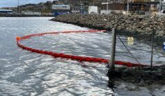 A red rope in the water next to a dock.