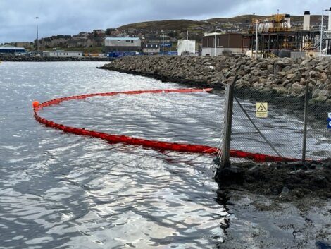 A red rope in the water next to a dock.