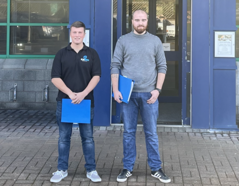 Two men standing in front of a building.