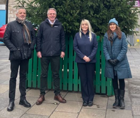 Four people standing in front of a green fence.