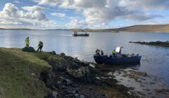 A boat is docked on a rocky shore.