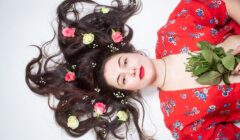 A woman laying down with flowers in her hair.