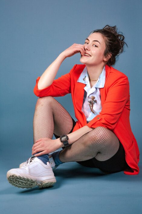 A woman in a red jacket sitting on the floor.