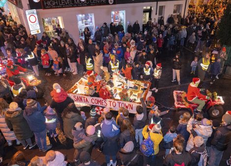 A crowd of people watching a santa claus parade.