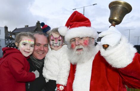 Santa claus and his family pose with a bell.