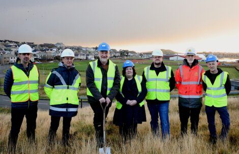 A group of people in safety vests and helmets standing in a field.