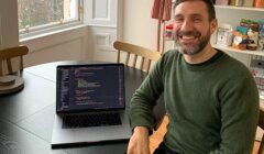 A man sitting at a table with a laptop in front of him.