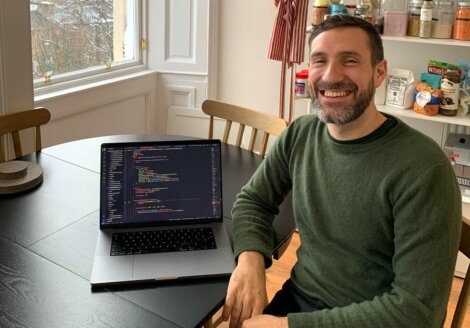 A man sitting at a table with a laptop in front of him.