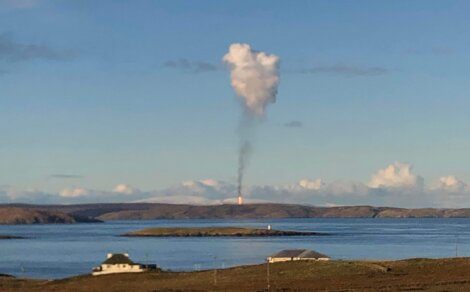 A smoke cloud in the sky over water.