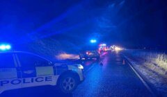 A police car and police cars on a road at night.