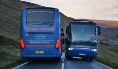 A blue bus driving down a road.